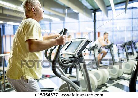 Stock Photo - Man using exercise machine. Fotosearch