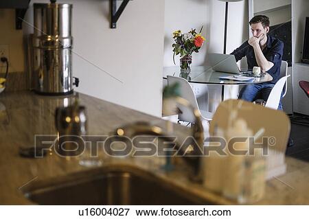 Stock Photo - Man working on laptop at home. Fotosearch