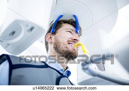 Stock Image - Mid Adult man having dental x-ray. Fotosearch
