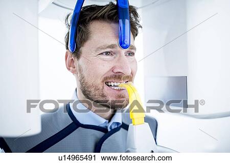 Stock Image - Mid Adult man having dental x-ray. Fotosearch
