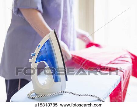 Stock Photography - Mid-section of woman ironing shirt. Fotosearch