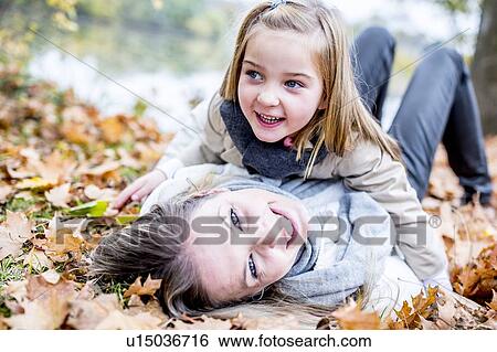 Mother and daughter lying on leaves View Large Photo Image Stock Photograph - Mother and daughter lying on leaves. Fotosearch