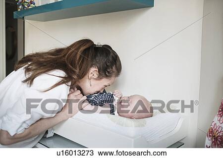 Stock Image - Mother kissing baby daughter (2-5 months). Fotosearch