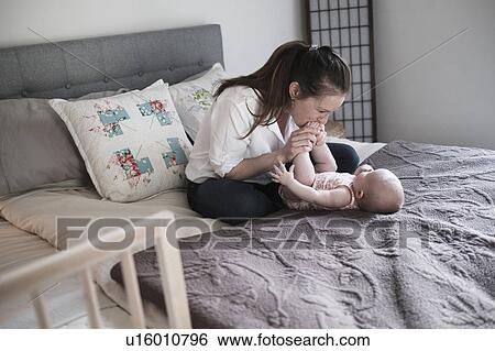 Mother kissing baby daughter's (2-5 month) feet in bedroom View Large Photo Image Stock Photograph - Mother kissing baby daughter's (2-5 month) feet in bedroom. Fotosearch