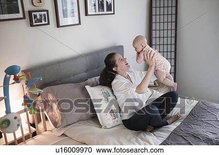 Mother playing with baby daughter (2-5 months) in bedroom View Large Photo Image Stock Image - Mother playing with baby daughter (2-5 months) in bedroom. Fotosearch