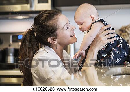 Mother playing with baby daughter (2-5 months) in kitchen View Large Photo Image Stock Image - Mother playing with baby daughter (2-5 months) in kitchen. Fotosearch