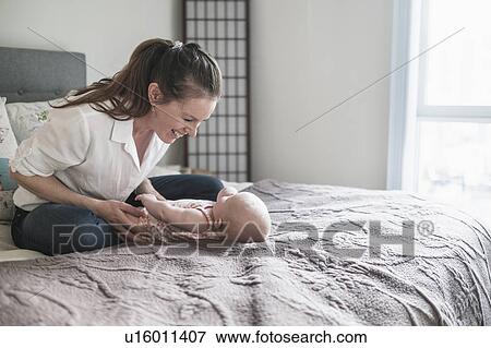 Mother playing with baby daughter (2-5 months) in bedroom View Large Photo Image Stock Photo - Mother playing with baby daughter (2-5 months) in bedroom. Fotosearch