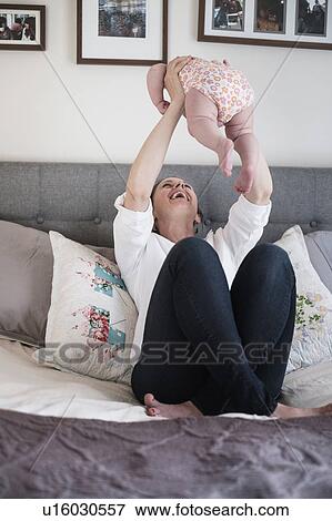 Mother playing with baby daughter (2-5 months) in bedroom View Large Photo Image Stock Photo - Mother playing with baby daughter (2-5 months) in bedroom. Fotosearch