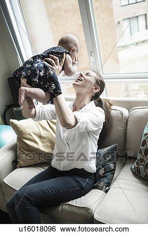 Mother playing with baby daughter (2-5 months) in living room View Large Photo Image Stock Photograph - Mother playing with baby daughter (2-5 months) in living room. Fotosearch
