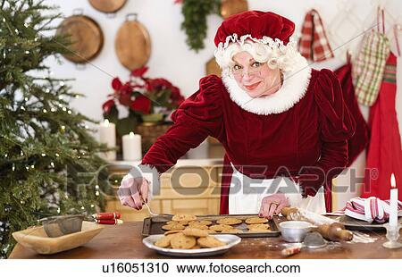 Stock Image - Mrs. Claus making gingerbread cookies. Fotosearch