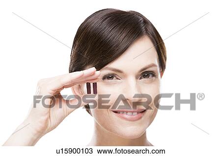 Stock Image - Portrait of beautiful woman holding capsules. Fotosearch