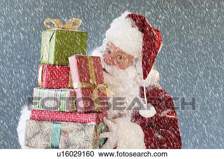 Stock Image - Portrait of Santa Claus carrying Christmas presents. Fotosearch