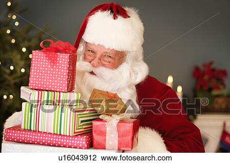 Stock Image - Portrait of Santa Claus holding Christmas presents. Fotosearch