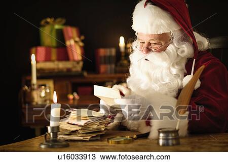 Stock Image - Portrait of Santa Claus reading child's letter at desk. Fotosearch