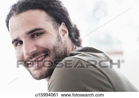 Stock Image - Portrait of young man with long curly hair. Fotosearch