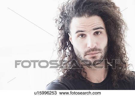 Stock Image - Portrait of young man with long curly hair. Fotosearch