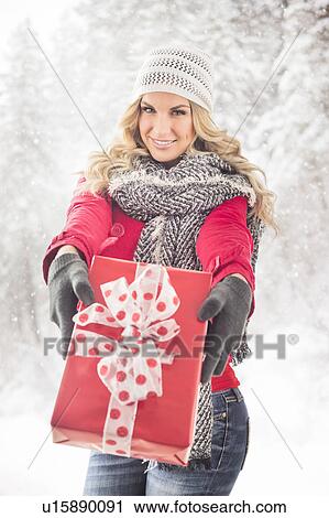 Portrait of young woman holding Christmas present View Large Photo Image Stock Image - Portrait of young woman holding Christmas present. Fotosearch
