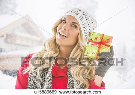 Portrait of young woman holding Christmas present View Large Photo Image Stock Photo - Portrait of young woman holding Christmas present. Fotosearch
