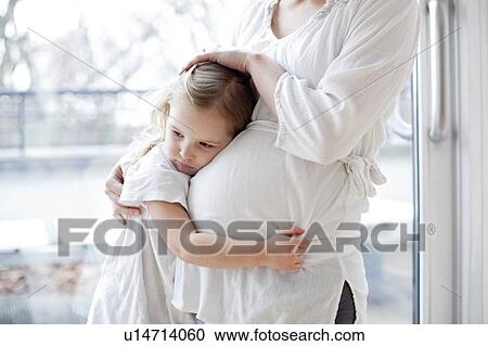 Stock Image - Pregnant mother with arms around daughter. Fotosearch