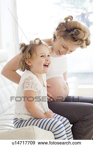 Stock Photo - Pregnant woman and daughter smiling. Fotosearch