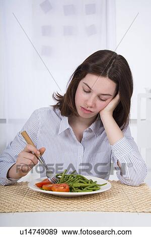 Stock Photo - Sad teenage girl with plate of vegetables. Fotosearch