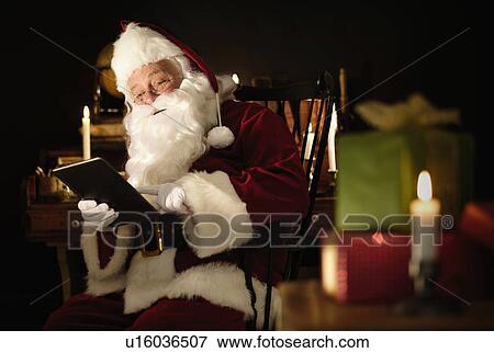 Stock Photo - Santa Claus using digital tablet. Fotosearch