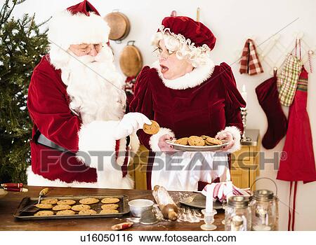 Santa stealing gingerbread cookie from Mrs. Claus View Large Photo Image Stock Photograph - Santa stealing gingerbread cookie from Mrs. Claus. Fotosearch