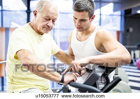Stock Photo - Senior man exercising with trainer. Fotosearch