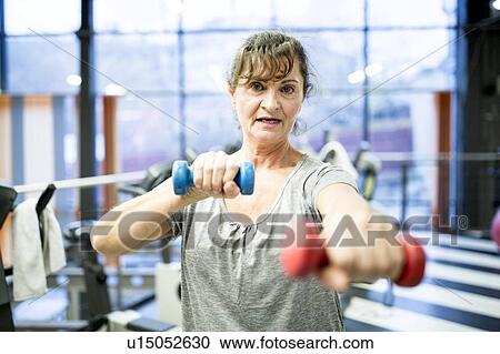 Stock Image - Senior woman holding dumbbell. Fotosearch