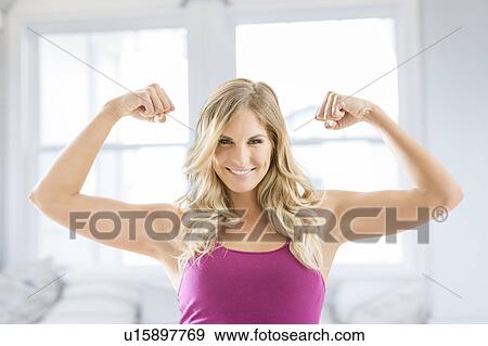 Smiling blonde woman flexing muscles View Large Photo Image Stock Photo - Smiling blonde woman flexing muscles. Fotosearch