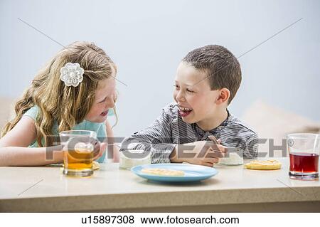 Smiling children (6-7, 8-9) eating pudding at table View Large Photo Image Stock Photo - Smiling children (6-7, 8-9) eating pudding at table. Fotosearch
