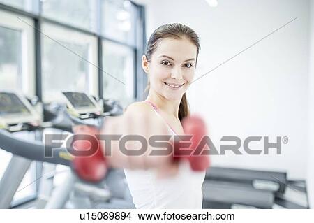 Smiling young woman holding dumbbell View Large Photo Image Picture - Smiling young woman holding dumbbell. Fotosearch