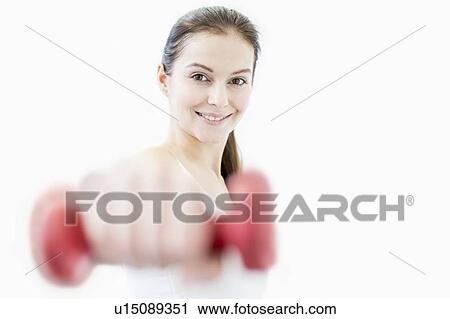 Stock Image - Smiling young woman holding dumbbell. Fotosearch