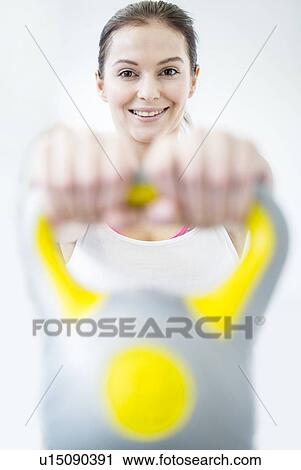 Smiling young woman holding kettlebell View Large Photo Image Stock Image - Smiling young woman holding kettlebell. Fotosearch