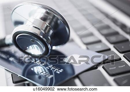 Stock Image - Stethoscope and credit card lying on laptop. Fotosearch