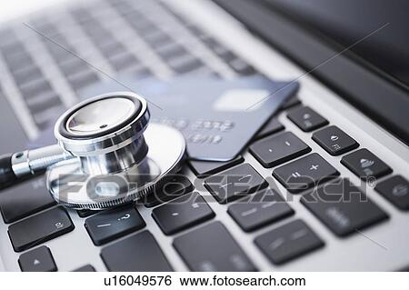 Stock Photograph - Stethoscope and credit card lying on laptop. Fotosearch