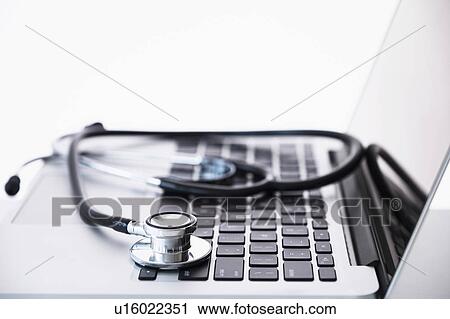 Stock Image - Stethoscope lying on laptop. Fotosearch