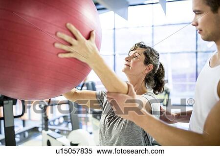 Trainer training woman with fitness ball View Large Photo Image Stock Photography - Trainer training woman with fitness ball. Fotosearch