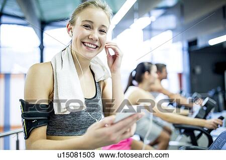 Stock Image - Woman adjusting headphones. Fotosearch