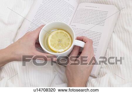 Stock Image - Woman holding cup and book. Fotosearch