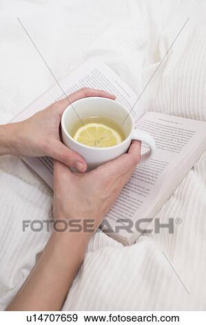 Stock Photo - Woman holding cup and book. Fotosearch