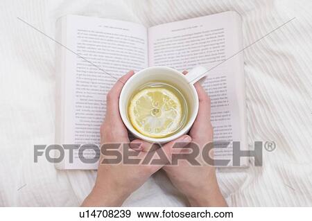 Stock Photo - Woman holding cup and book. Fotosearch