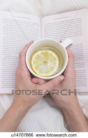 Stock Photograph - Woman holding cup and book. Fotosearch