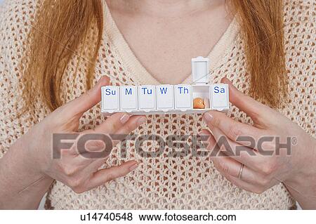 Stock Photo - Woman holding pill organiser. Fotosearch