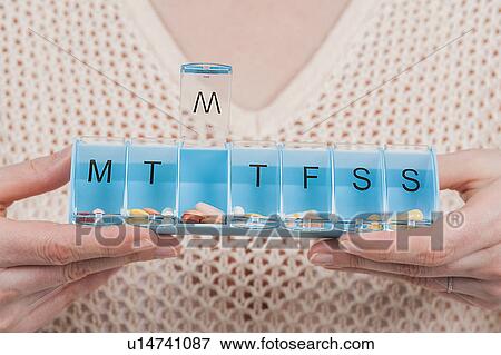 Stock Photo - Woman holding pill organiser. Fotosearch