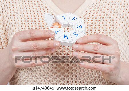 Stock Photography - Woman holding pill organiser. Fotosearch
