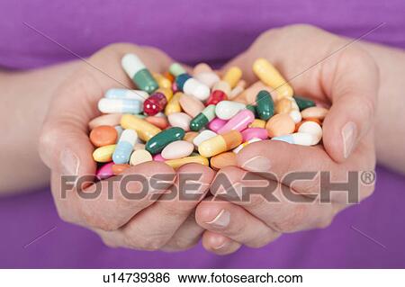 Stock Photograph - Woman holding tablets in cupped hands. Fotosearch
