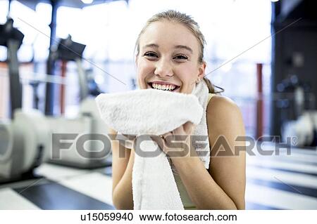 Stock Image - Woman holding towel after exercising. Fotosearch
