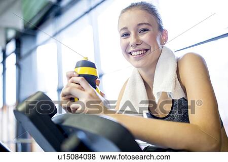 Stock Photo - Woman holding water bottle in gym. Fotosearch