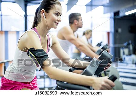 Stock Photo - Woman listening to music in gym. Fotosearch
